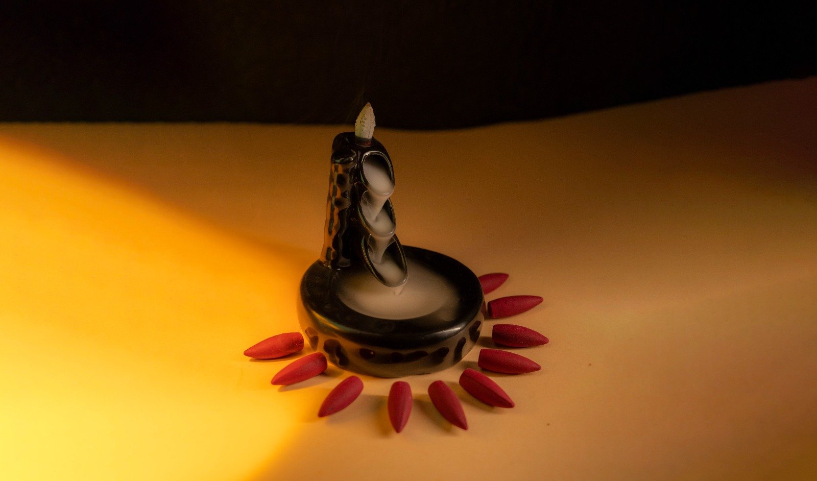 Black ceramic backflow incense burner stand with cascading smoke